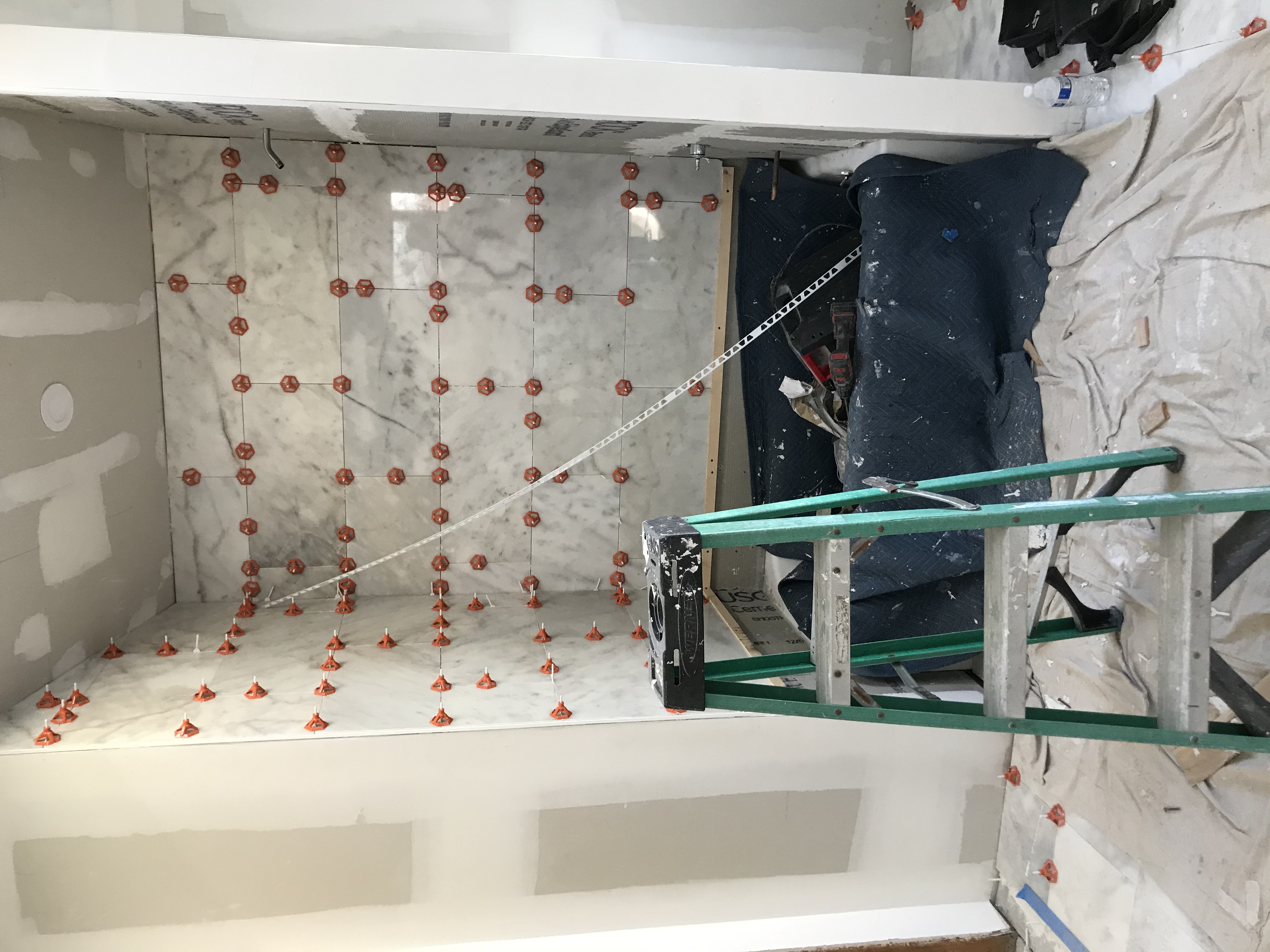 Marble shower tile being set with leveling clips