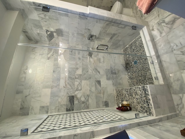 Bathroom after — custom walk-in shower with pebble floor and glass door