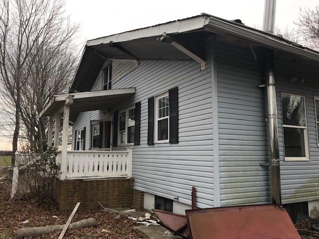 Exterior before — old siding and damaged trim