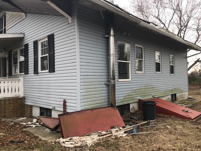 Exterior rear before — foundation and siding damage