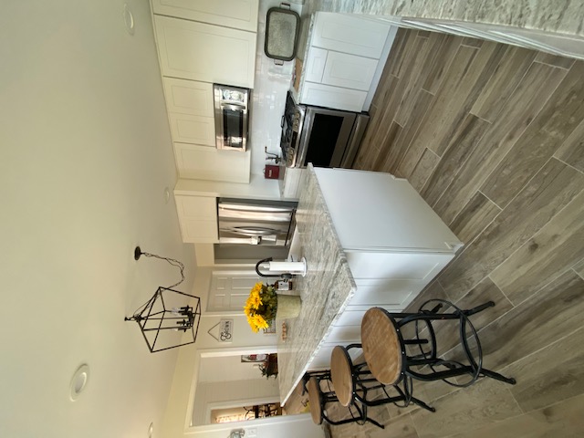 Kitchen after — stainless appliances, granite countertops, wood-look tile floor