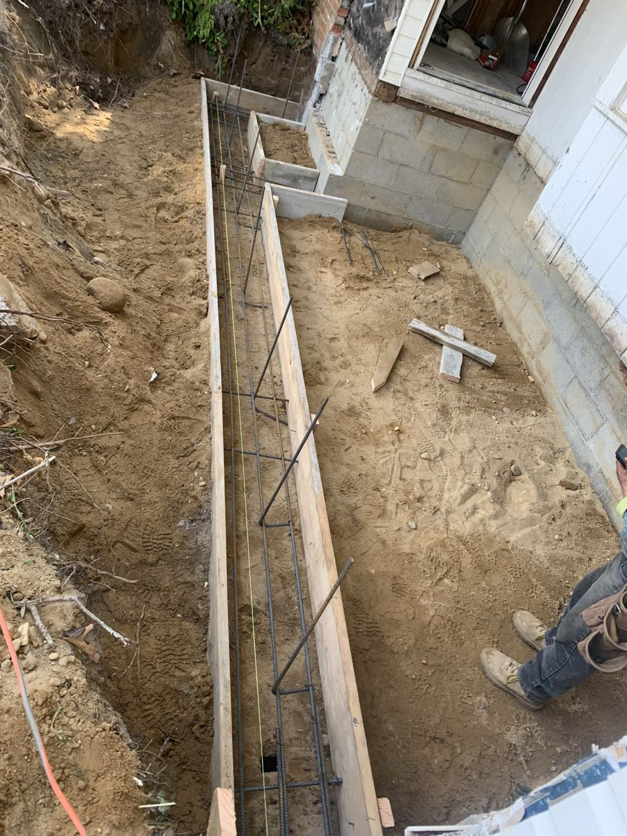 Greene Group crew setting footing forms and rebar next to an existing block foundation